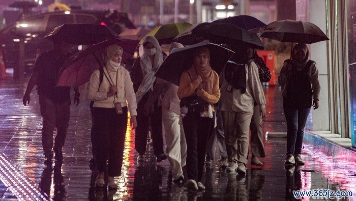 Warga berjalan menggunakan payung saat hujan mengguyur kawasan Jalan Sudirman, Jakarta, Senin (11/11/2024).